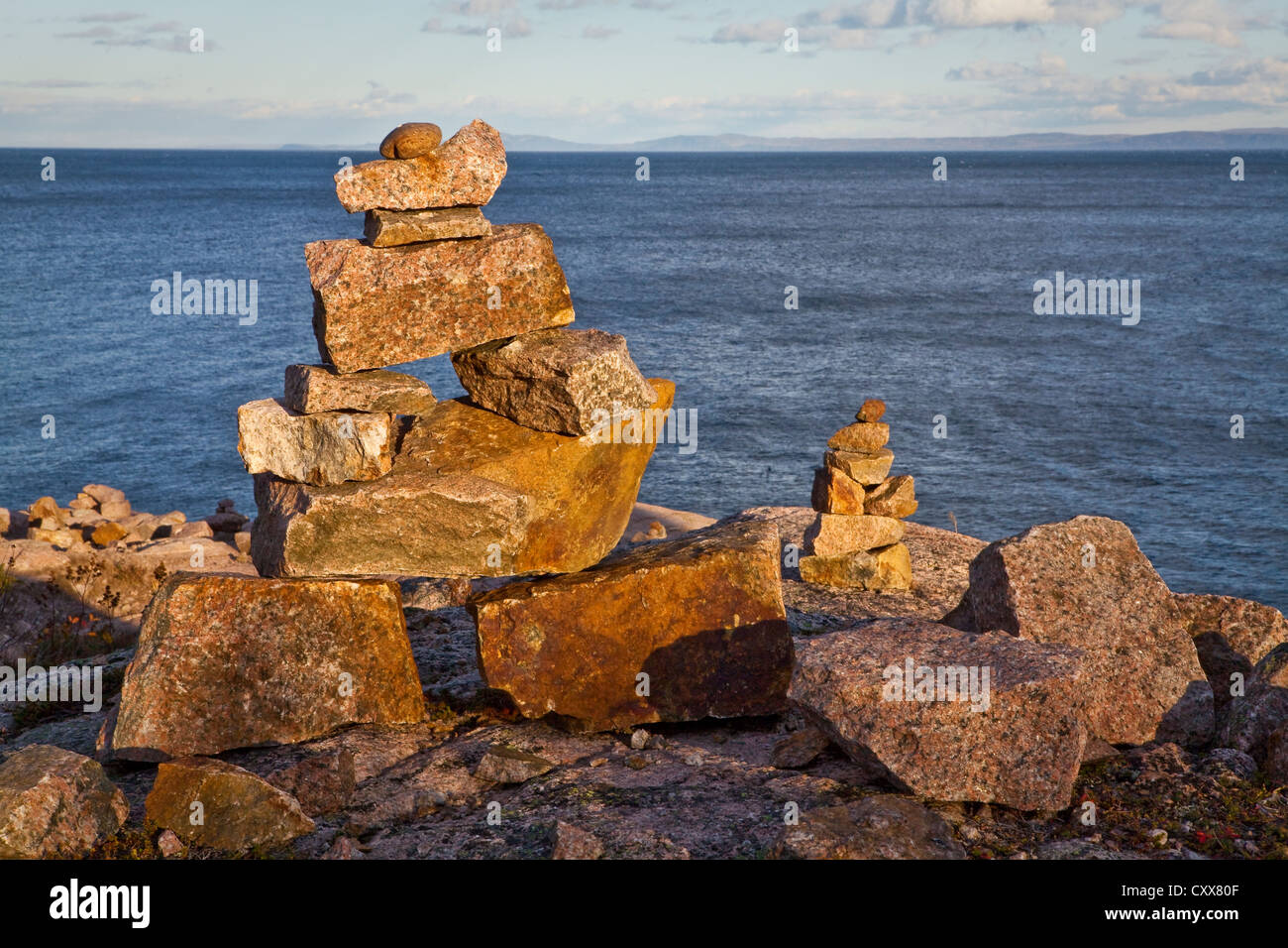 Sun sets on inuksuit (plural form of inuksuk) in front of the St. Lawrence river in the Essipit Innu community Stock Photo