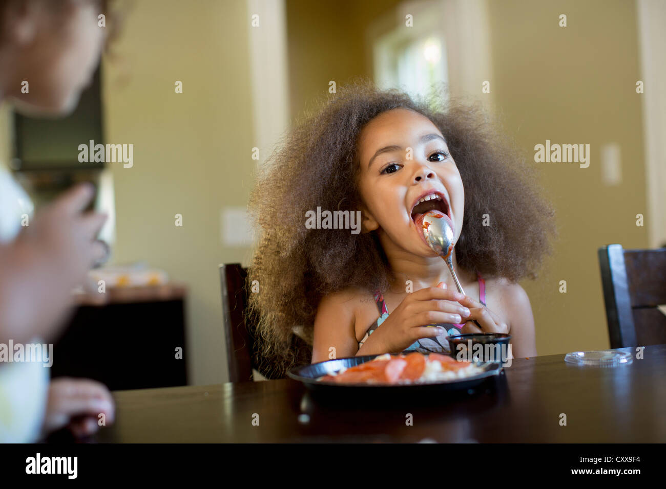 Mixed race girl eating dinner Stock Photo Alamy