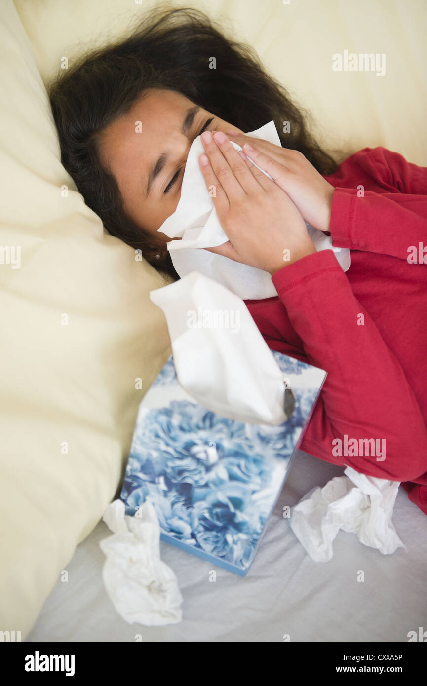Mixed race girl blowing her nose Stock Photo Alamy