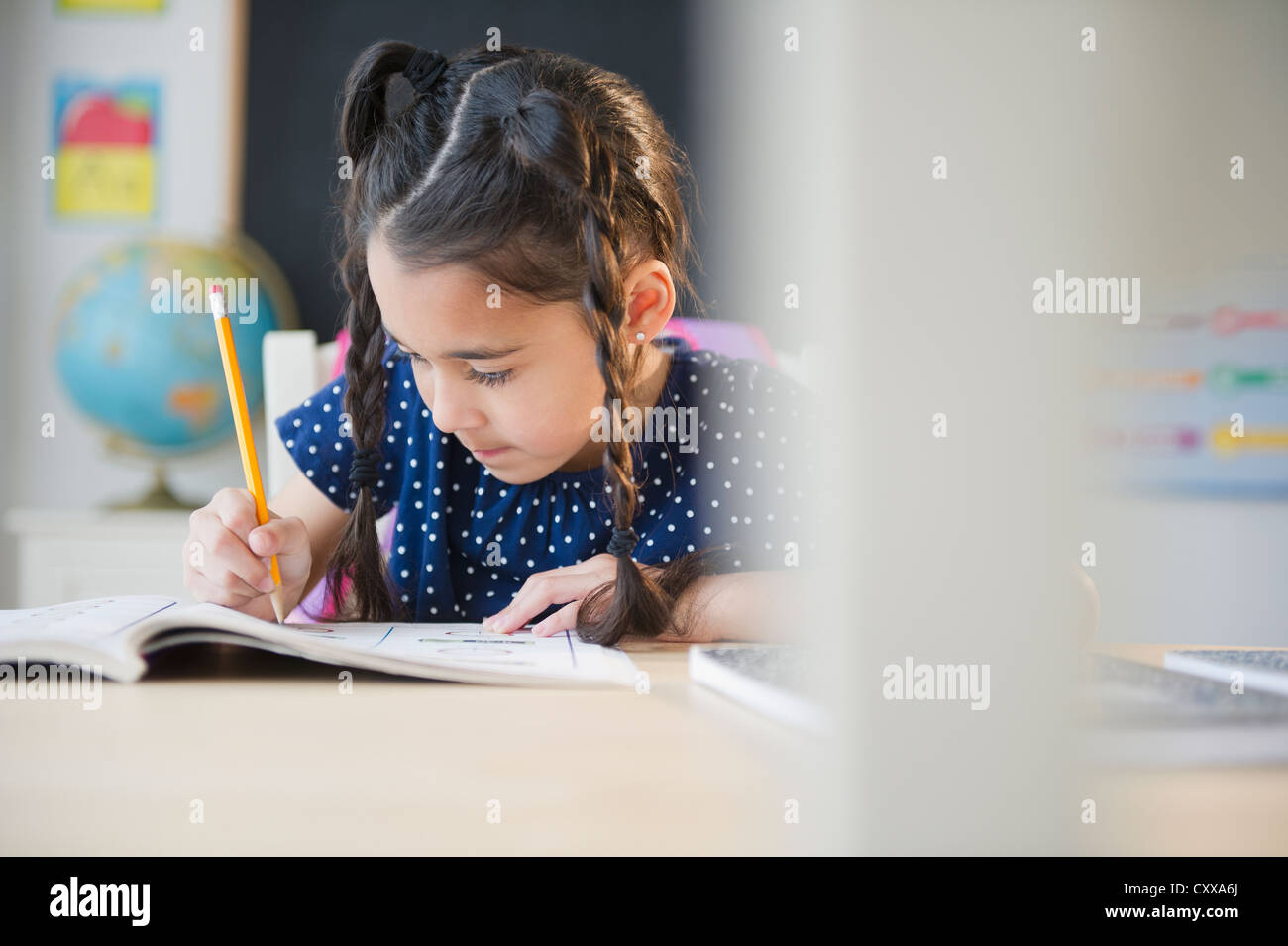 Mixed race girl writing in school Stock Photo