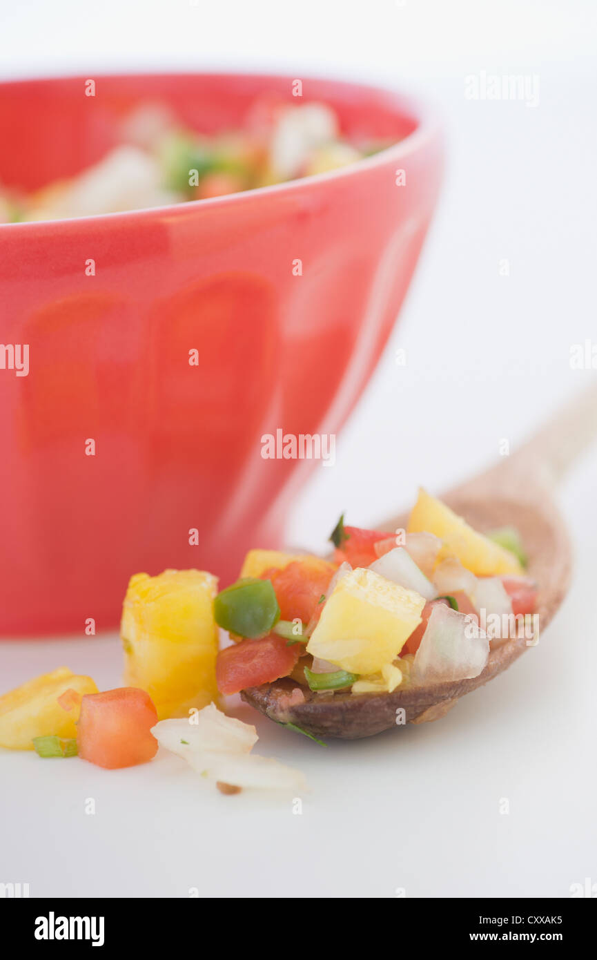 Spoonful of salsa next to bowl Stock Photo