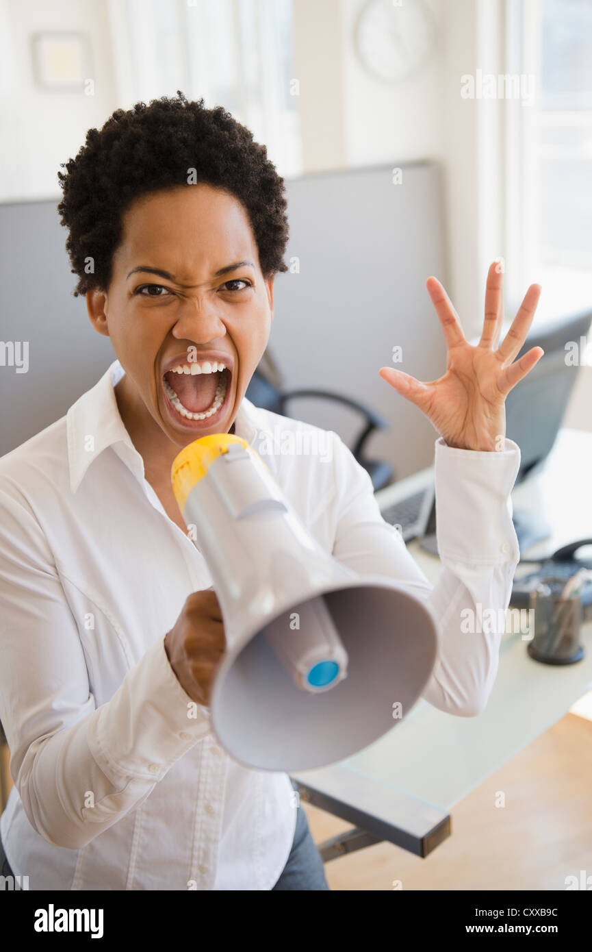 African American businesswoman using bullhorn in office Stock Photo