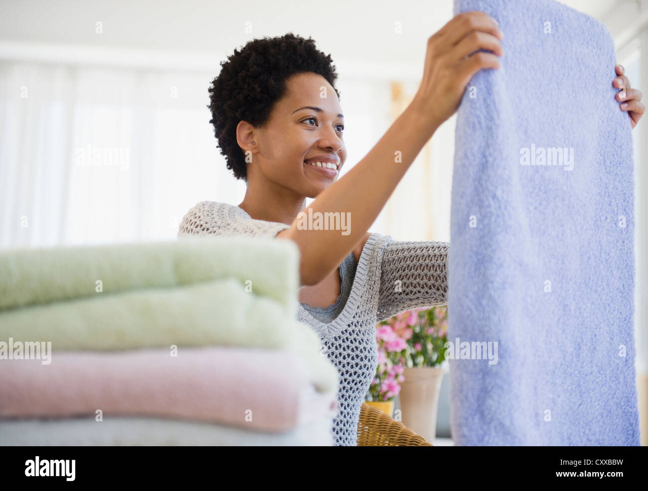 African American woman folding towels Stock Photo