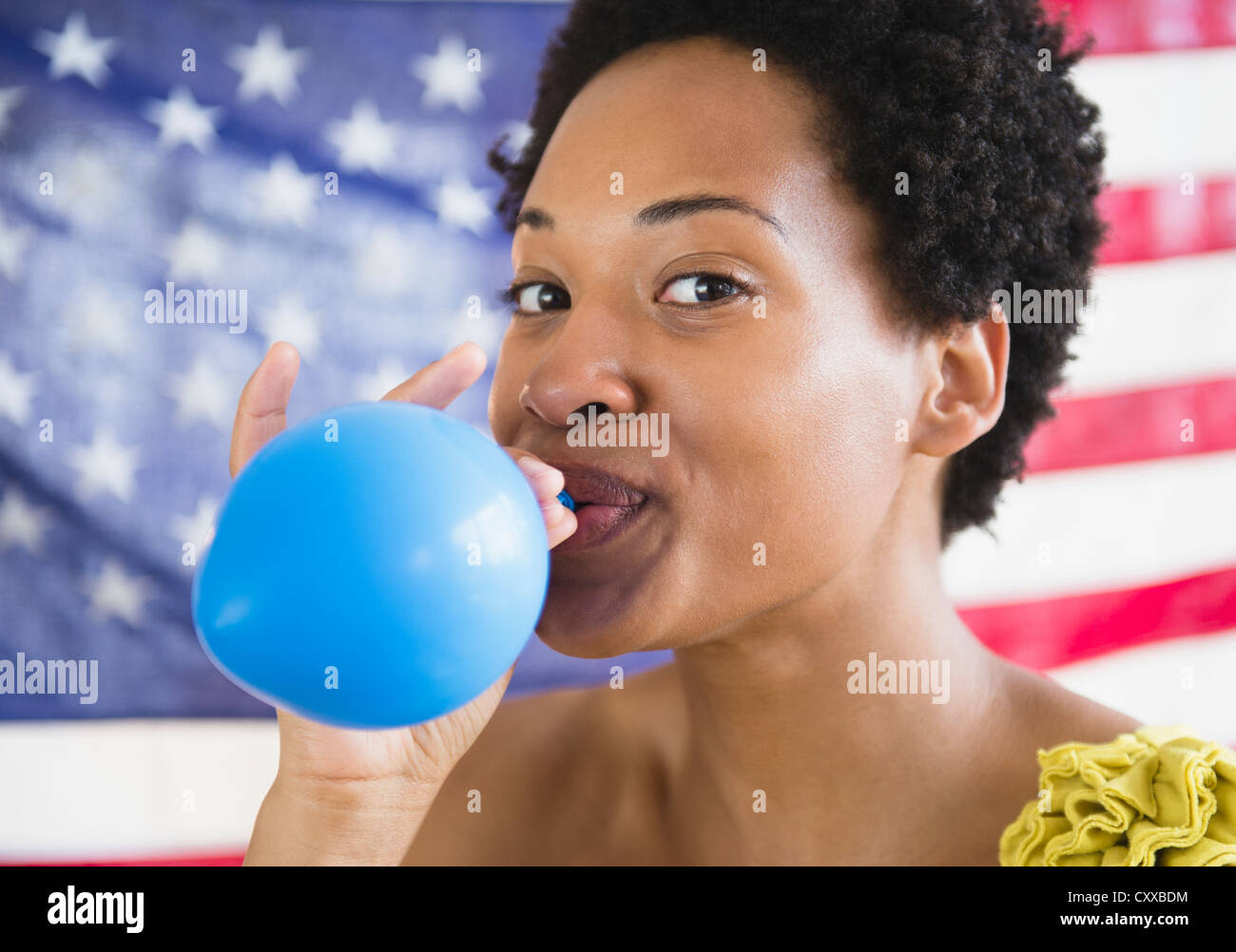 African American woman blowing up blue balloon Stock Photo