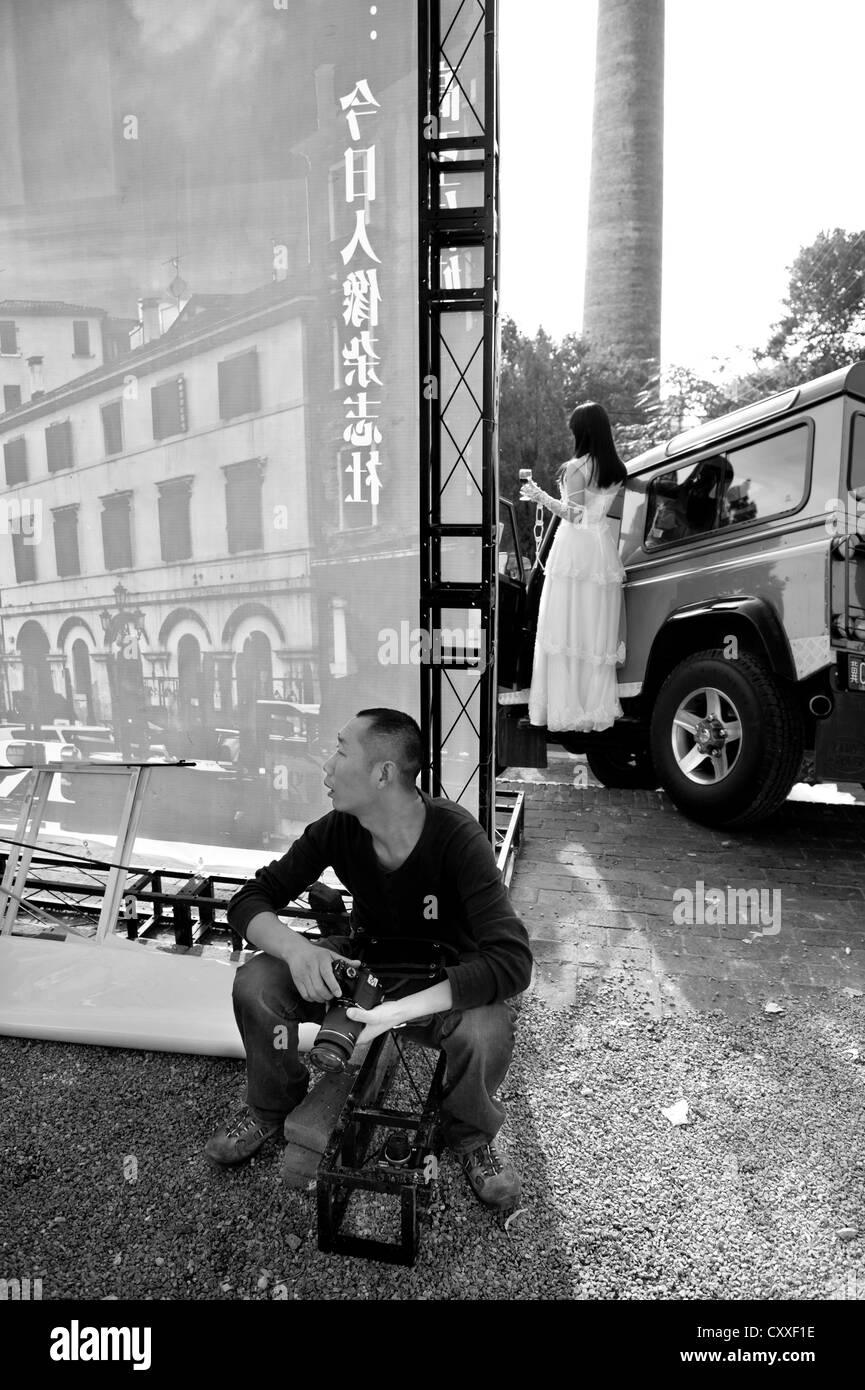 Pingyao, Shanxi, China. Photographer sitting backstage at a fashion show for wedding dresses. Stock Photo