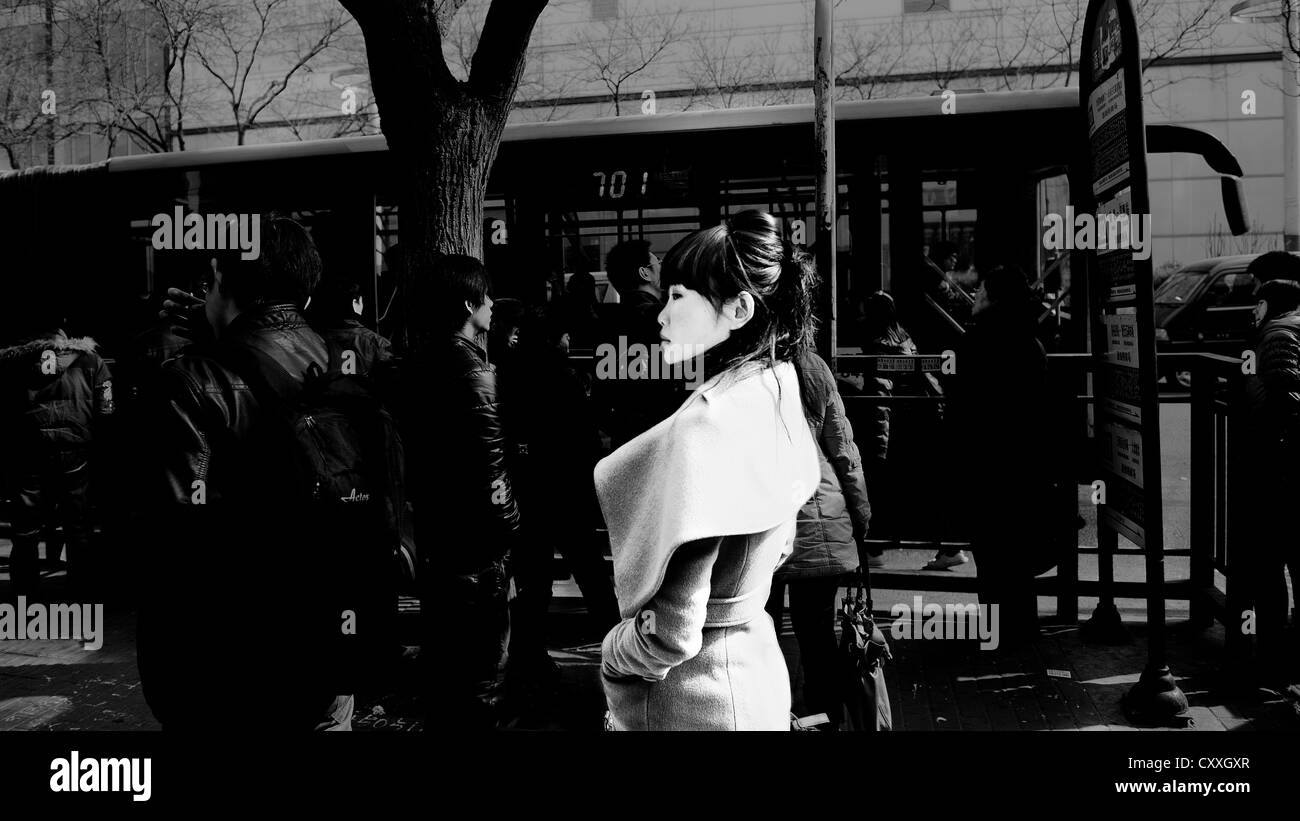 Lidu, Beijing. Woman waiting at a bus stop. Stock Photo