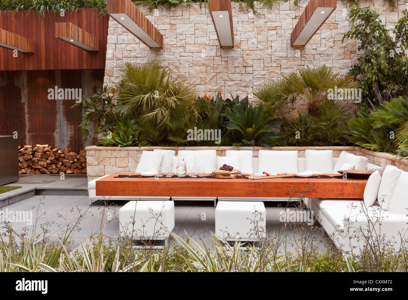 Urban modern contemporary garden with outside outdoor garden furniture sofa seating area stone paving paved patio Chelsea flower show gardens UK Stock Photo