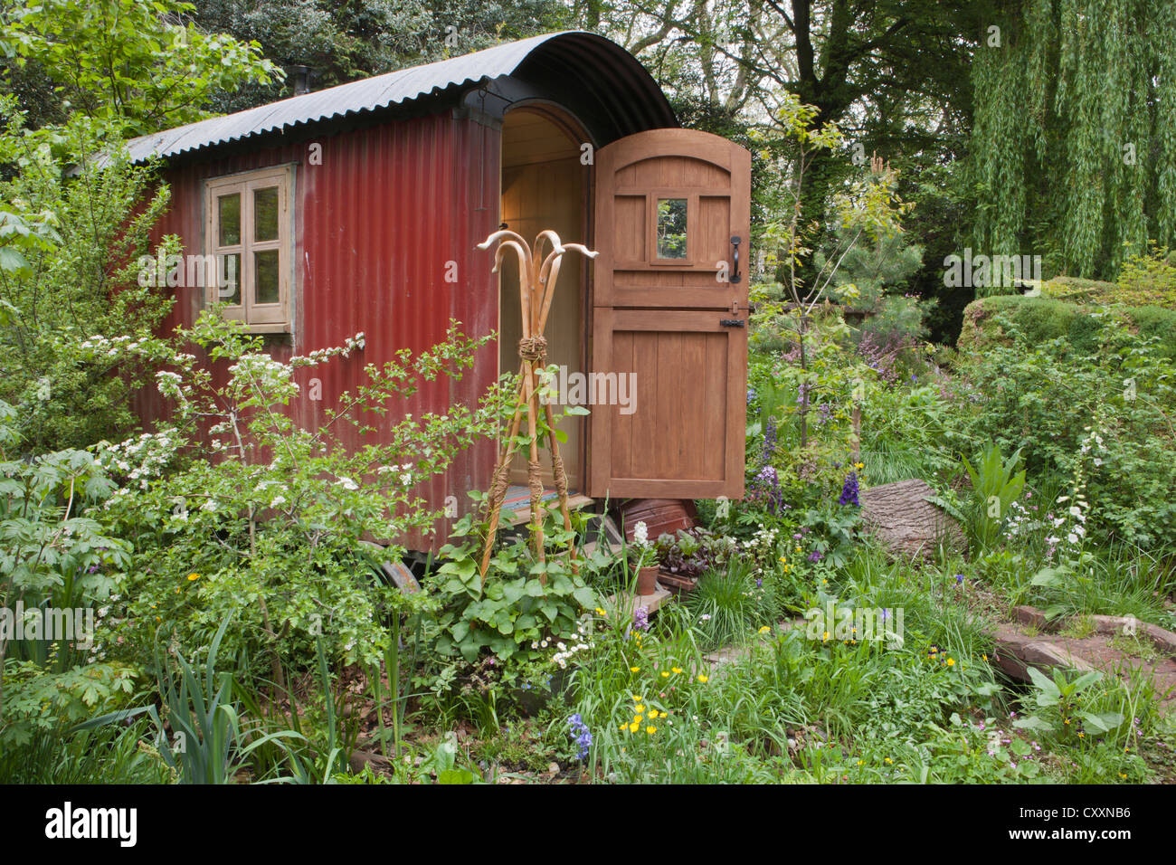 A sustainable eco friendly wildlife garden with shepherds hut cabin retreat in a woodland woods with wildflowers Spring summer UK chelsea flower show Stock Photo
