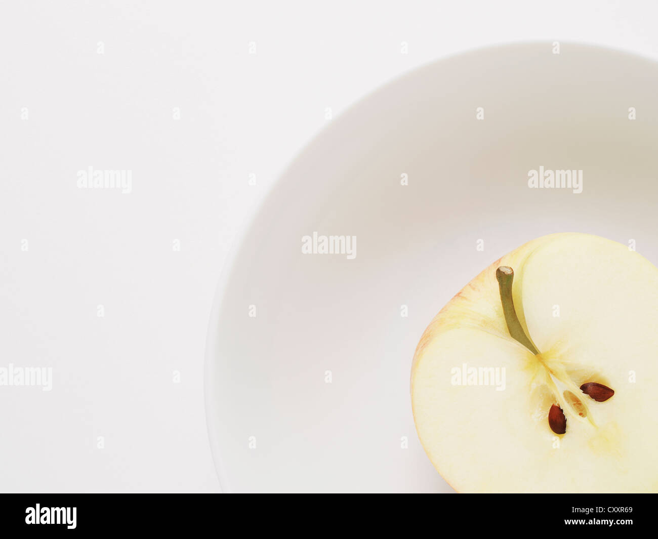 Half apple with core in white bowl Stock Photo