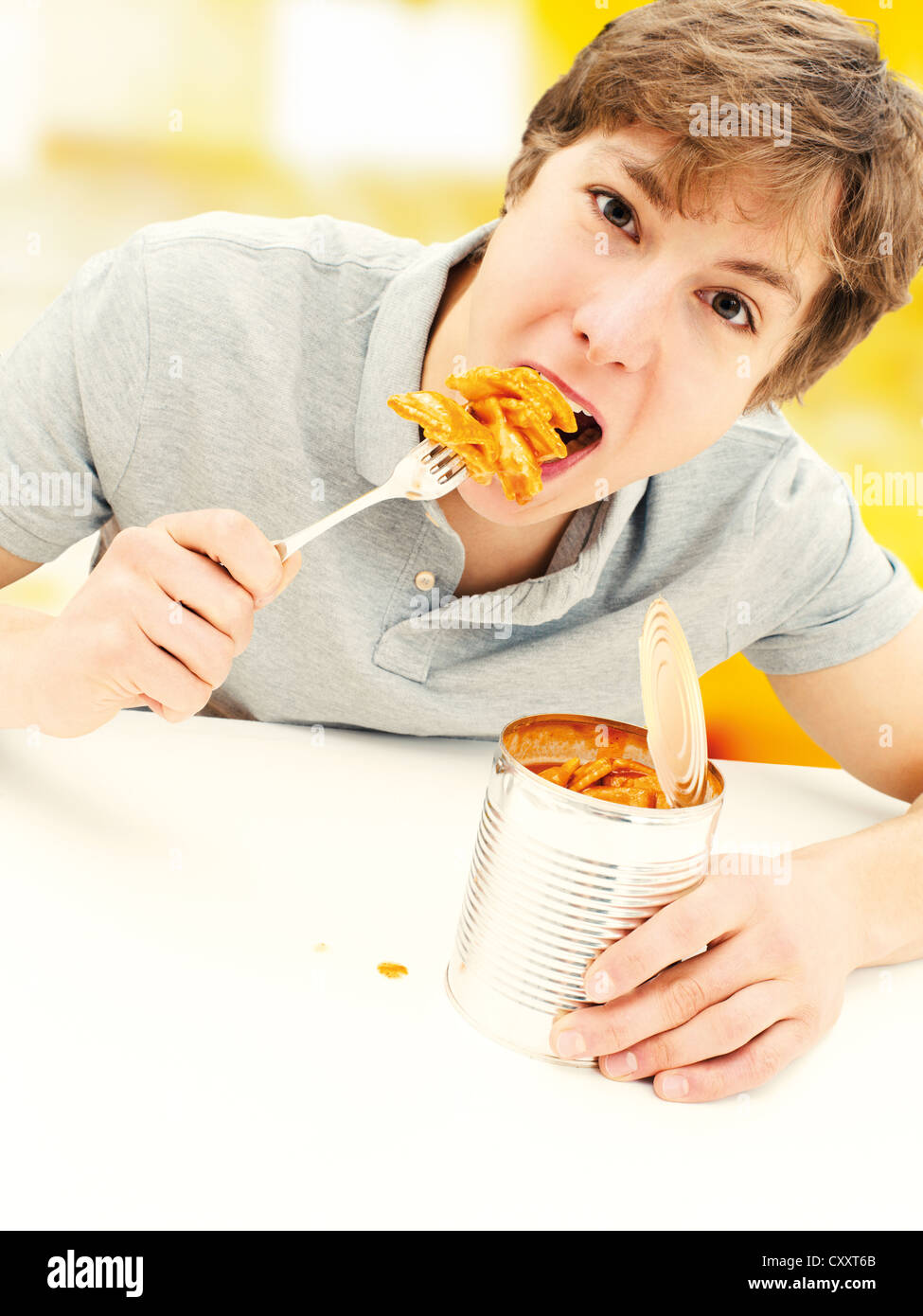 Young man eating ravioli from a tin can Stock Photo - Alamy