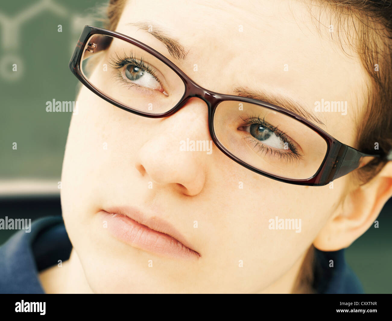 Girl wearing glasses, portrait, standing in front of a blackboard Stock Photo
