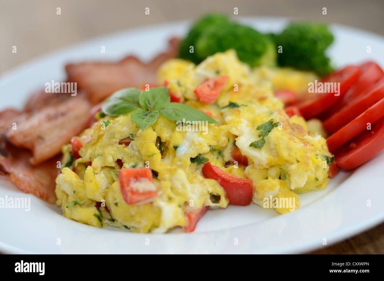 Scrambled eggs with fried bacon on the white plate Stock Photo - Alamy
