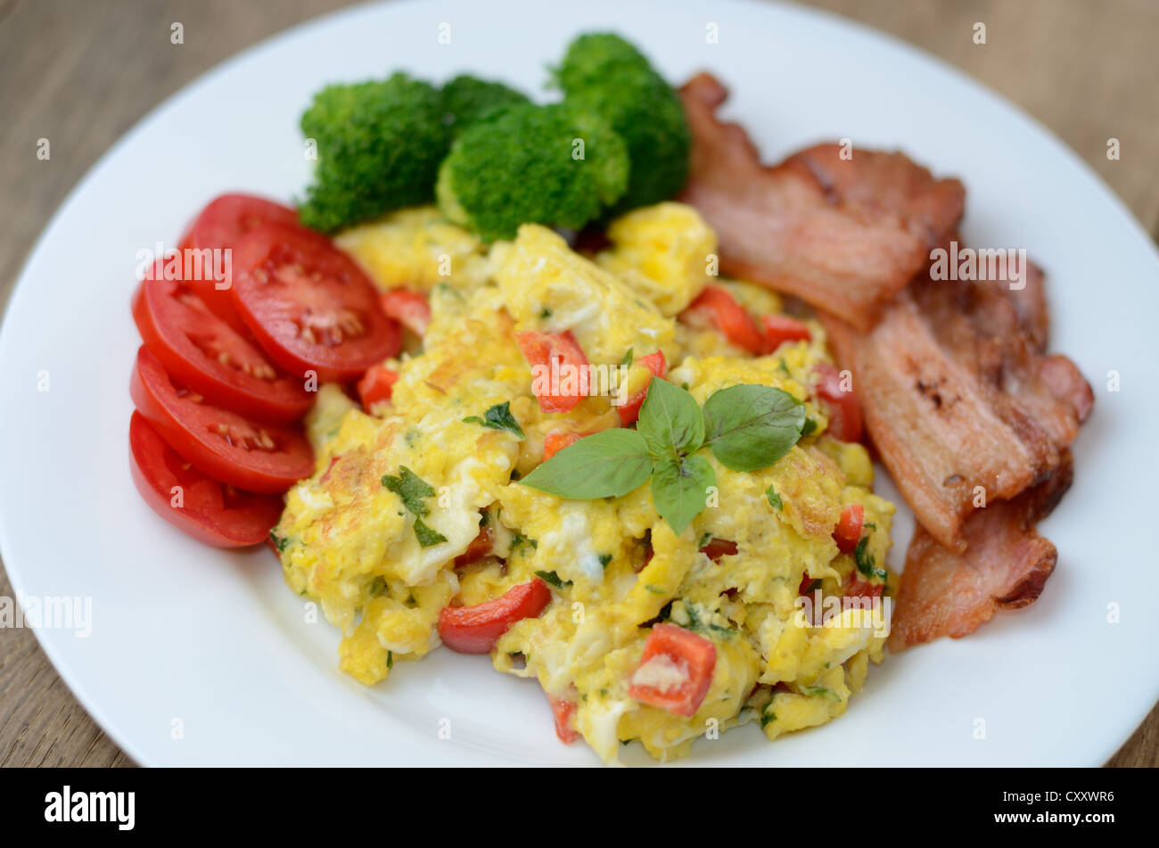 Scrambled eggs with fried bacon on the white plate Stock Photo - Alamy