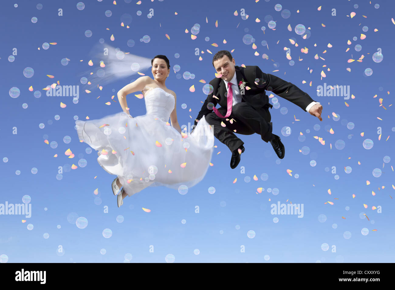 Bride and groom, bridal couple jumping in to the air, against a blue sky, bubbles, confetti Stock Photo