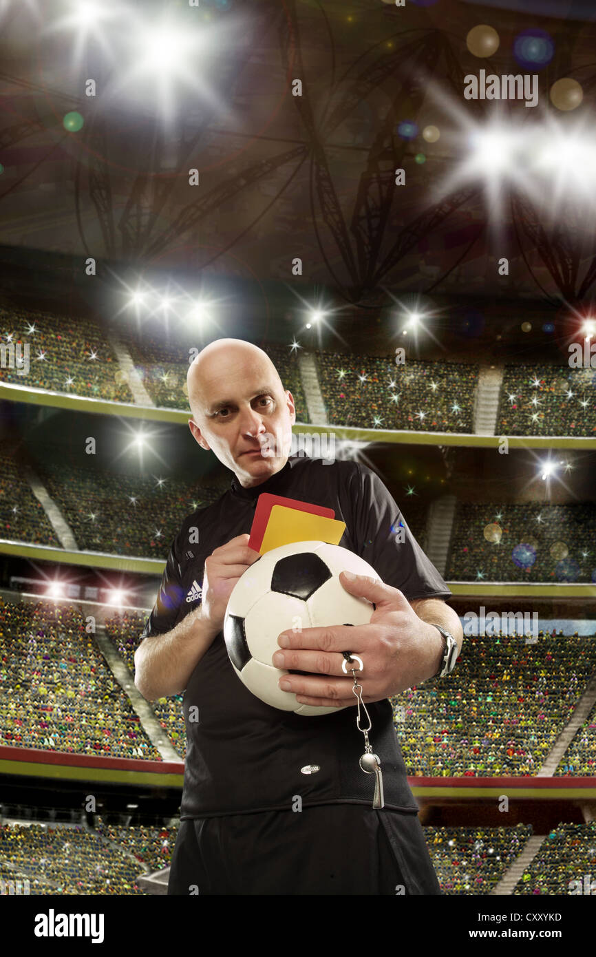 Referee holding a soccer ball, a yellow and a red card, soccer stadium Stock Photo