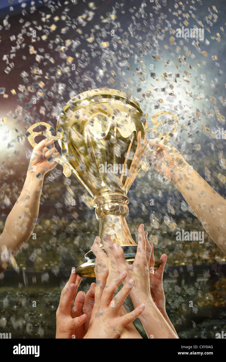 Hands holding up a trophy in a football stadium Stock Photo