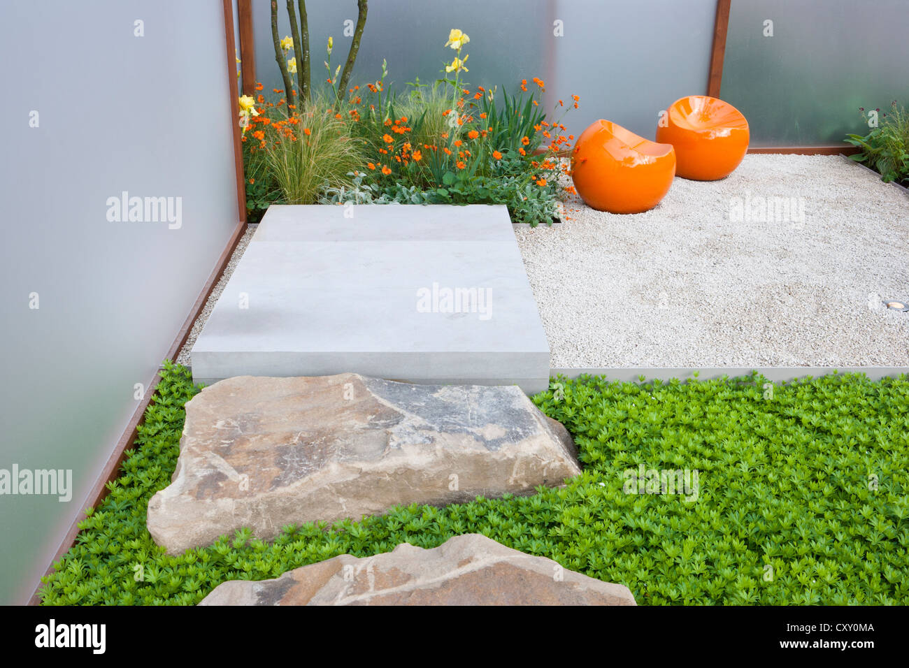 modern contemporary English small courtyard gravel garden with stone boulders and modern seating area patio Chelsea flower show UK Stock Photo