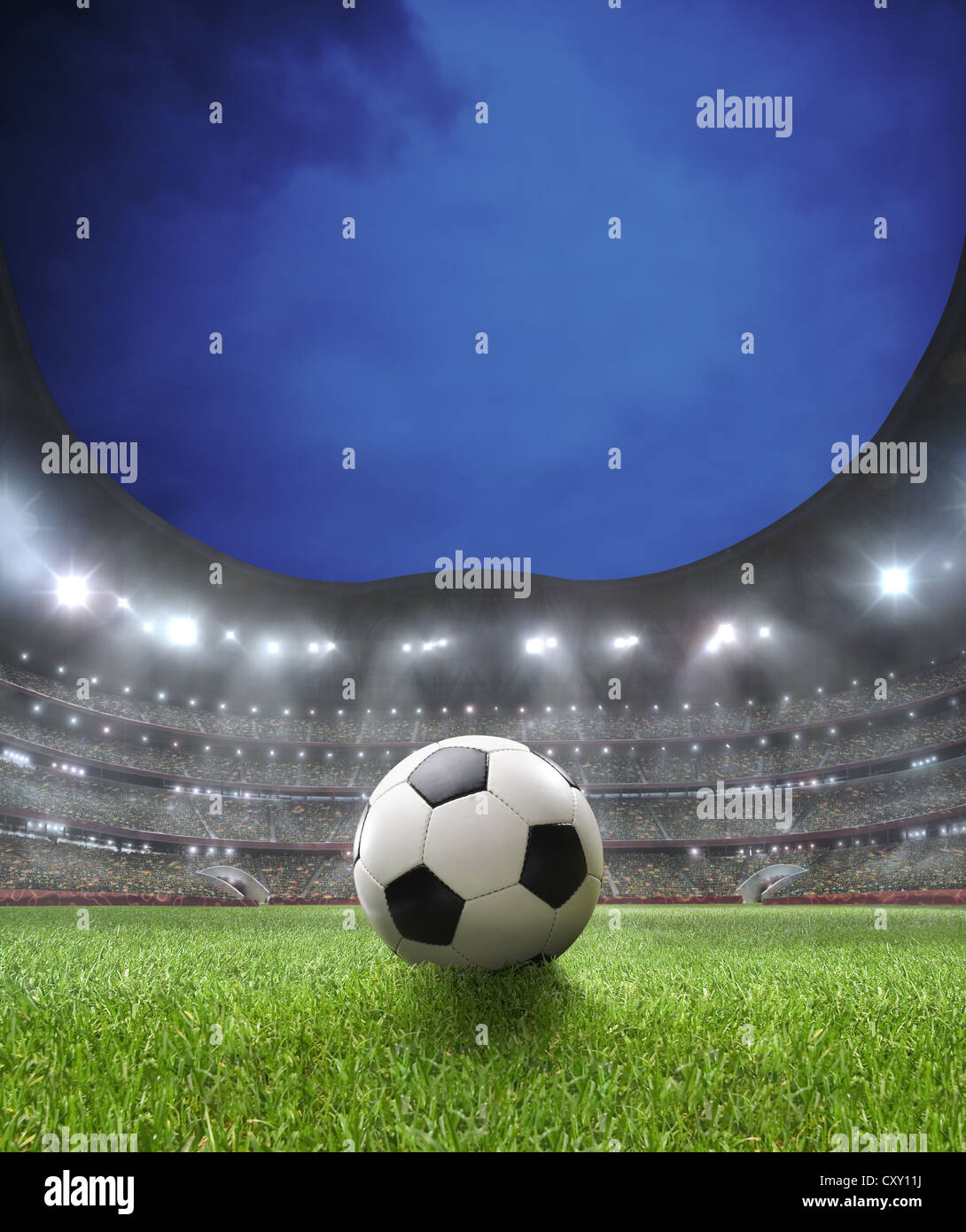 Soccer ball, lighted soccer stadium, lawn, grand stand Stock Photo