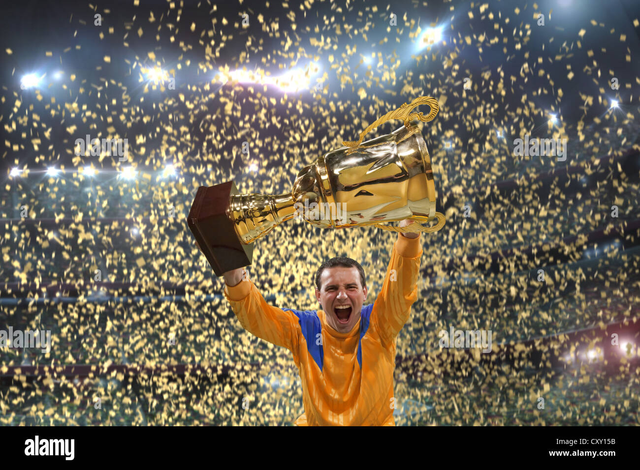 Football player holding up trophy, cheering, winner, winning, confetti, football stadium Stock Photo