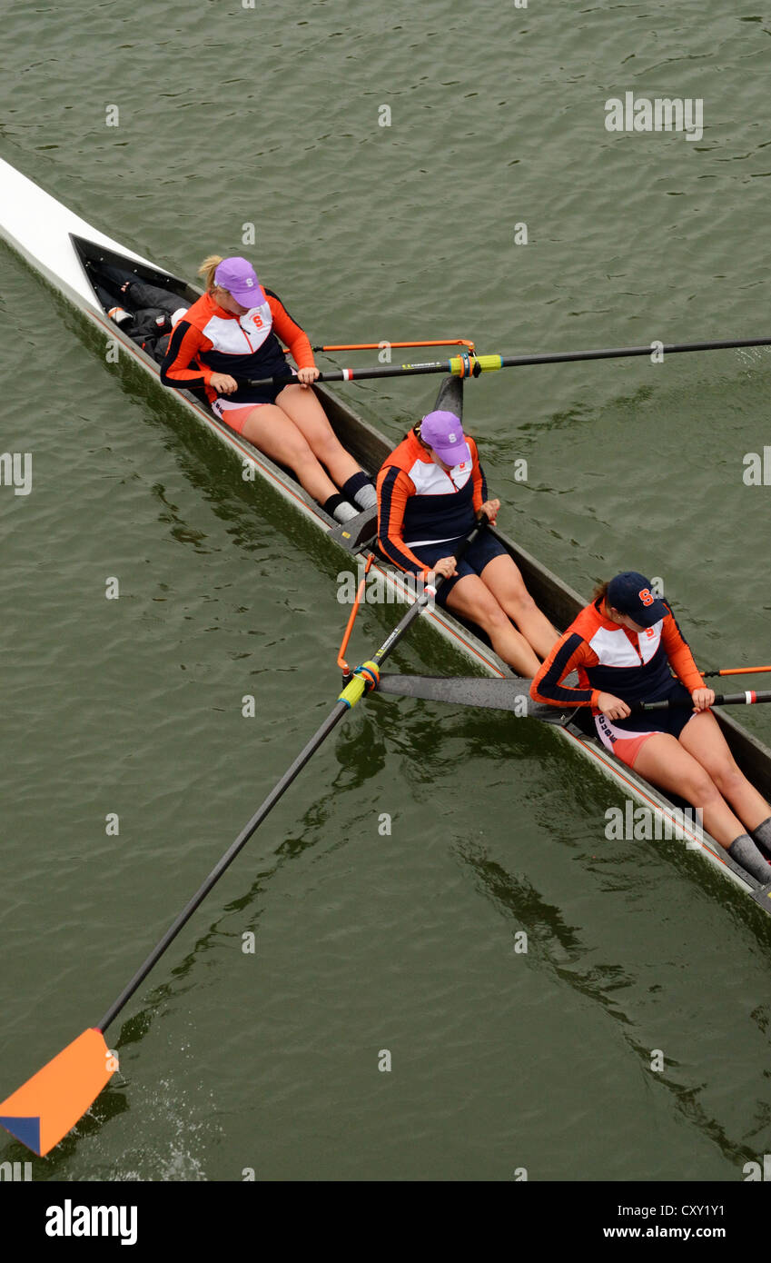 Three women in sculling boat rowing team compete in college race Stock