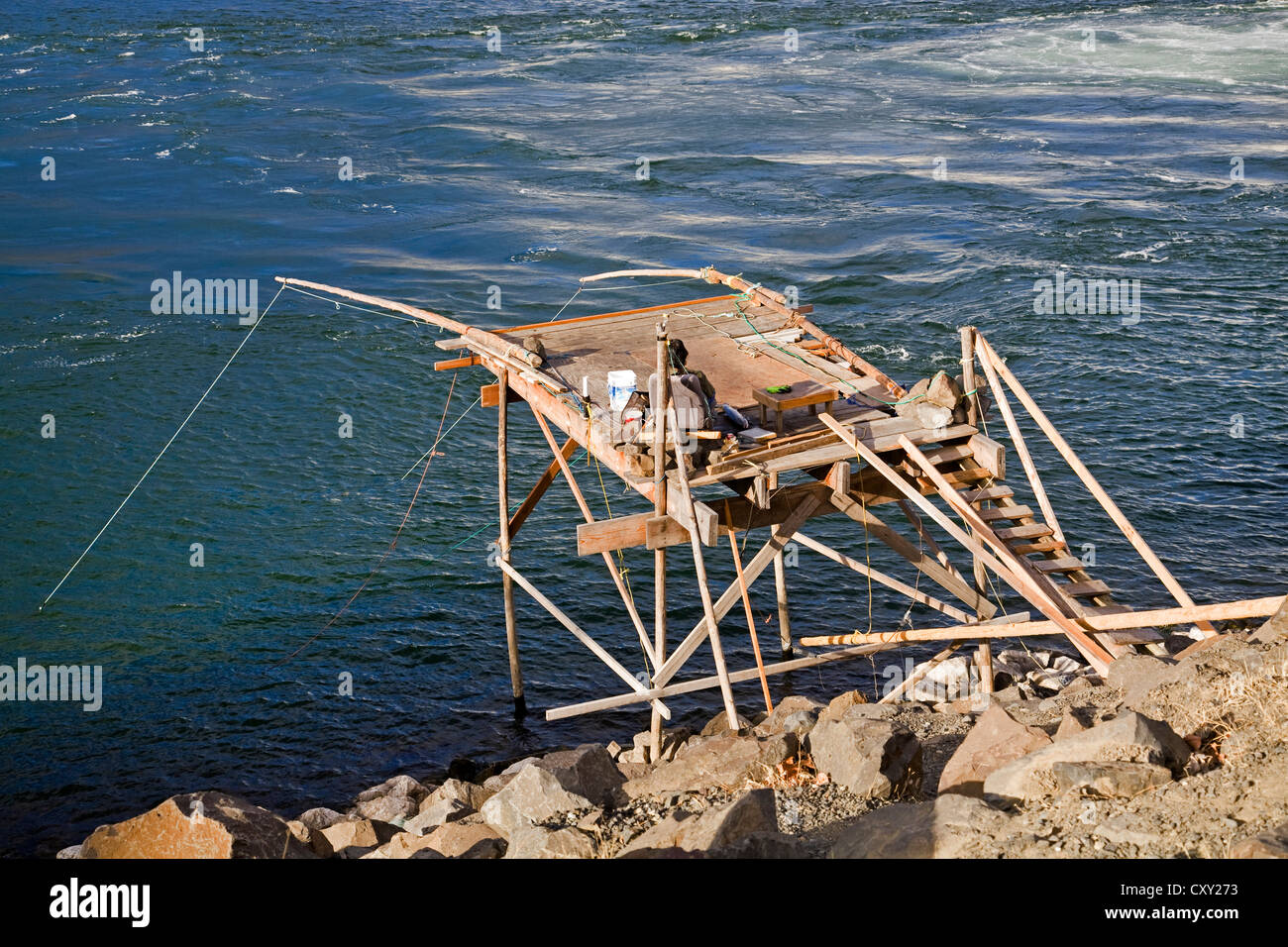 An Indian waits on a platform from which native american people fish for salmon on the Columbia River beneath John Day Dam. Stock Photo