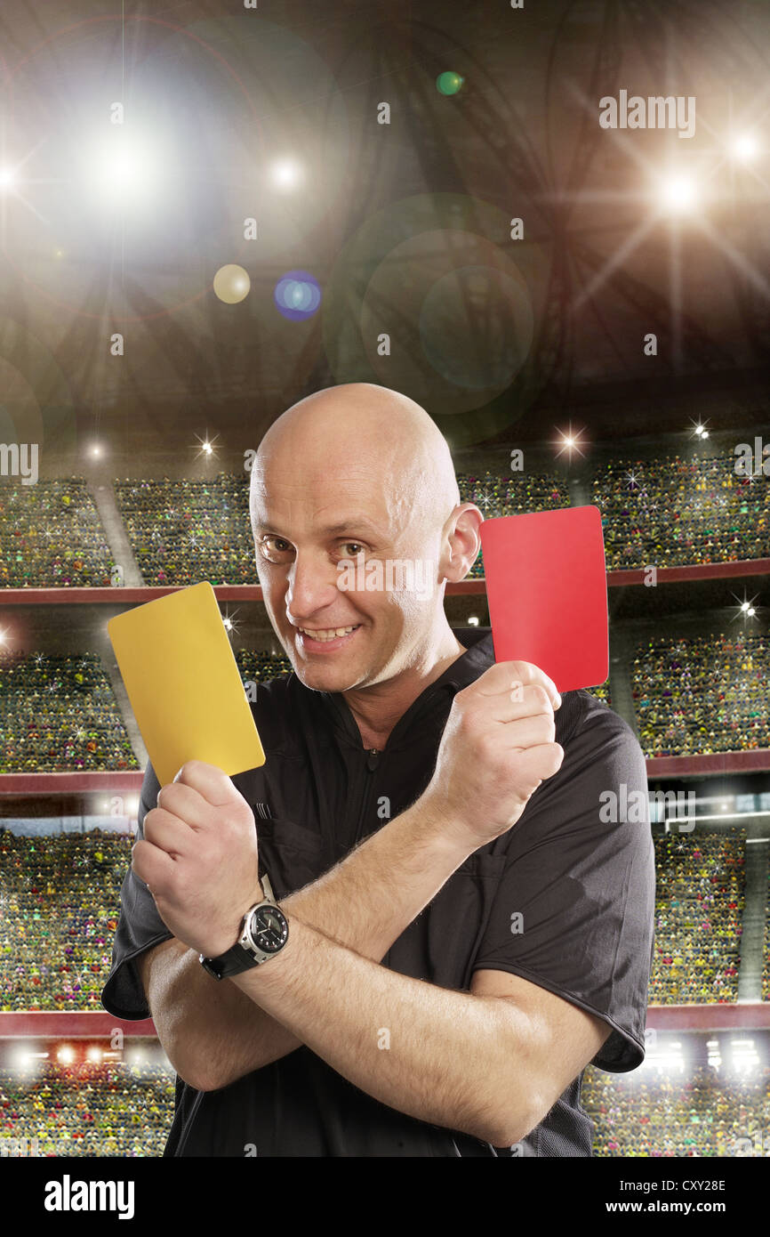 Referee holding a yellow and a red card, soccer stadium Stock Photo