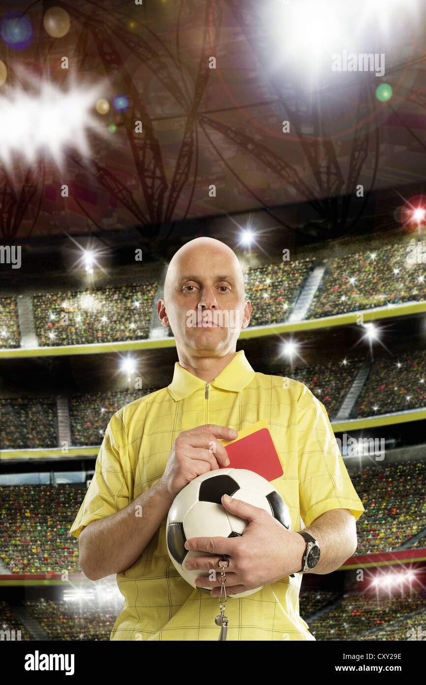 Referee holding a soccer ball and a red card, soccer stadium Stock Photo
