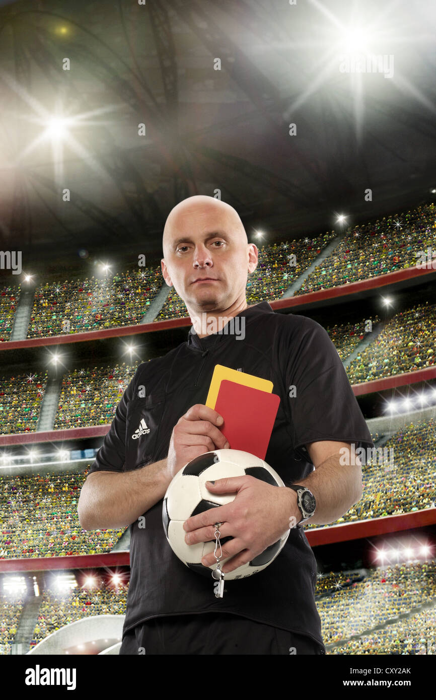 Referee holding a red and a yellow card, soccer stadium Stock Photo