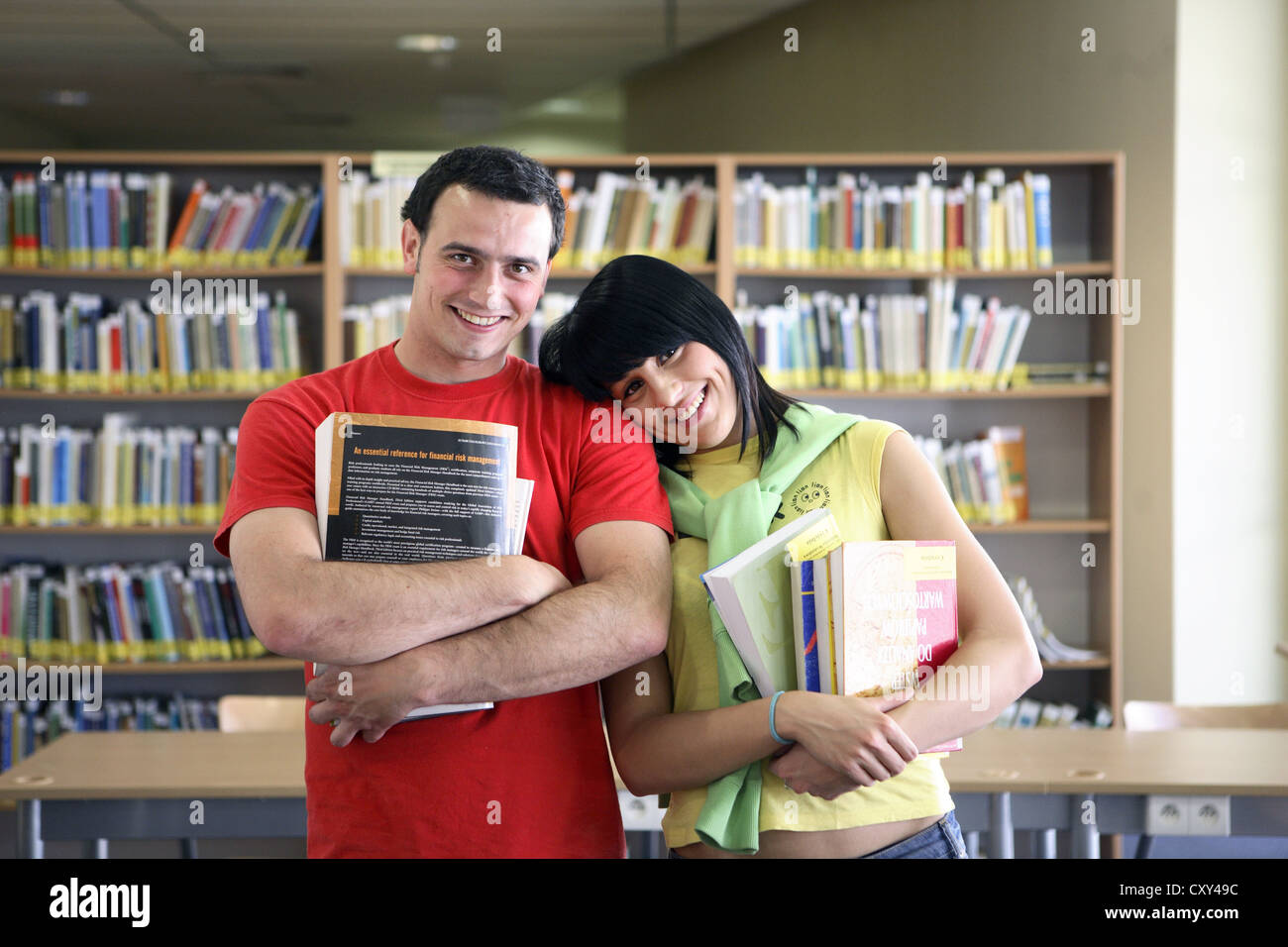 Male and female students holding books in a university library Stock ...