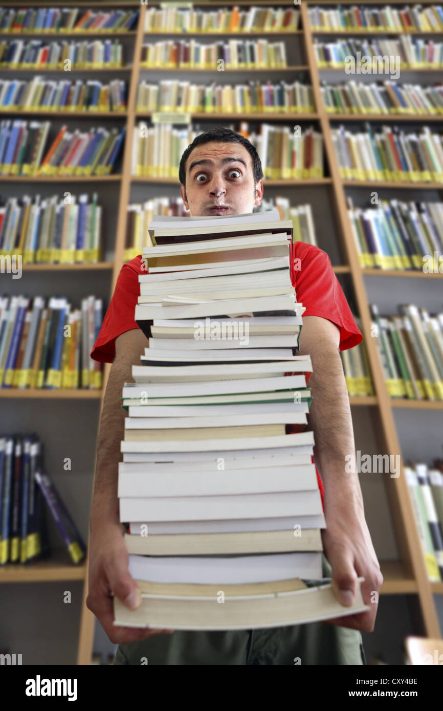 Stressed young man carrying books hires stock photography and images