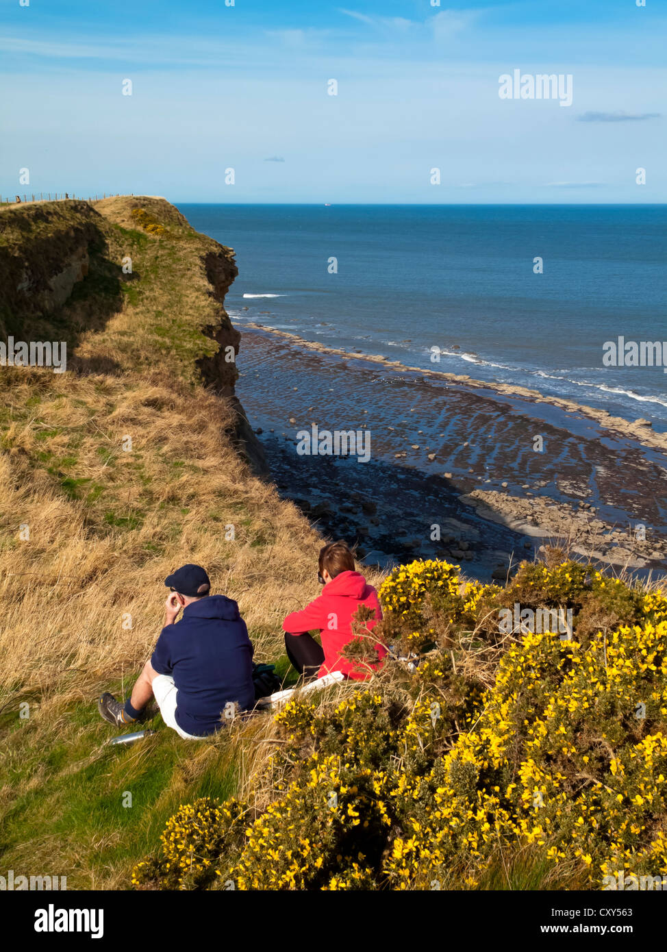 Walkers resting on clifftop on  the Cleveland Way Coastal Path between Robin Hood's Bay and Whitby in North Yorkshire England UK Stock Photo