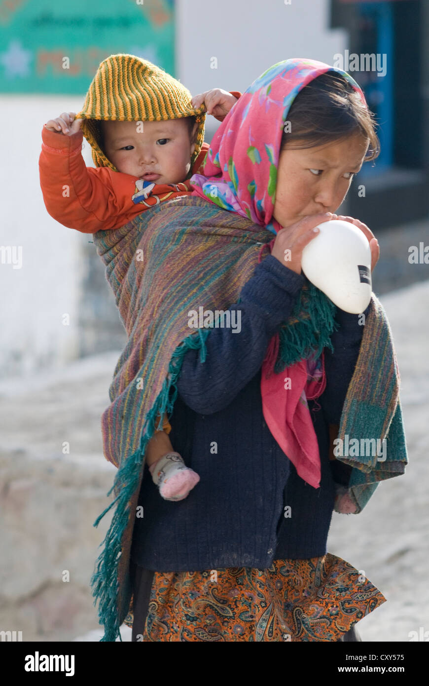 A young girl carries her sibling, slung across her back, in Mud village, Spiti, Northern India Stock Photo