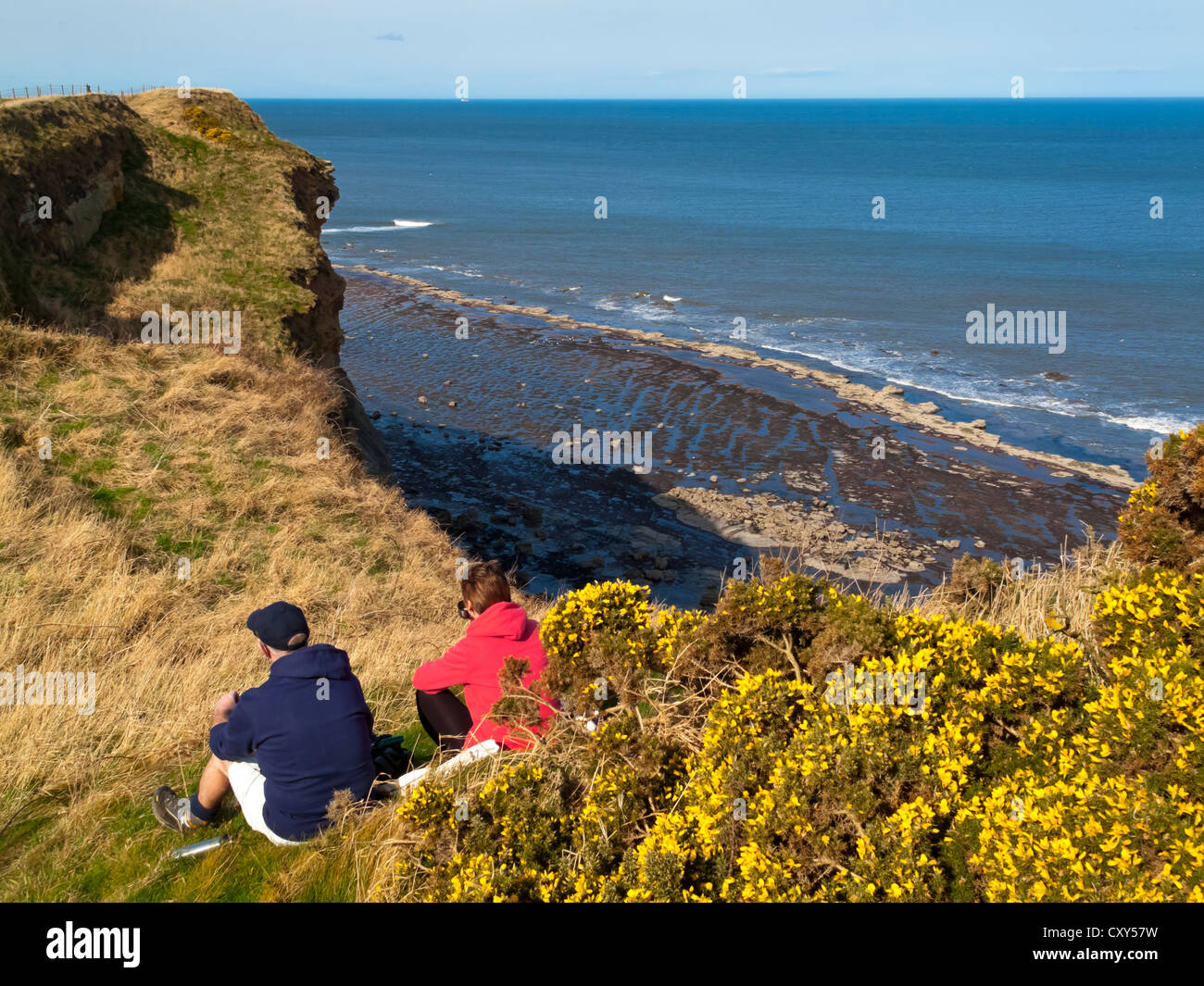 Walkers resting on clifftop on  the Cleveland Way Coastal Path between Robin Hood's Bay and Whitby in North Yorkshire England UK Stock Photo
