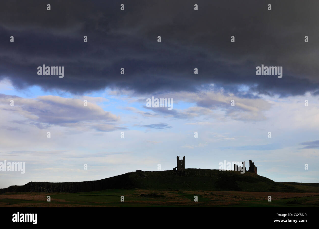 Storm clouds at dusk pass over Dunstanburgh Castle, Northumberland, England, #UK. Stock Photo