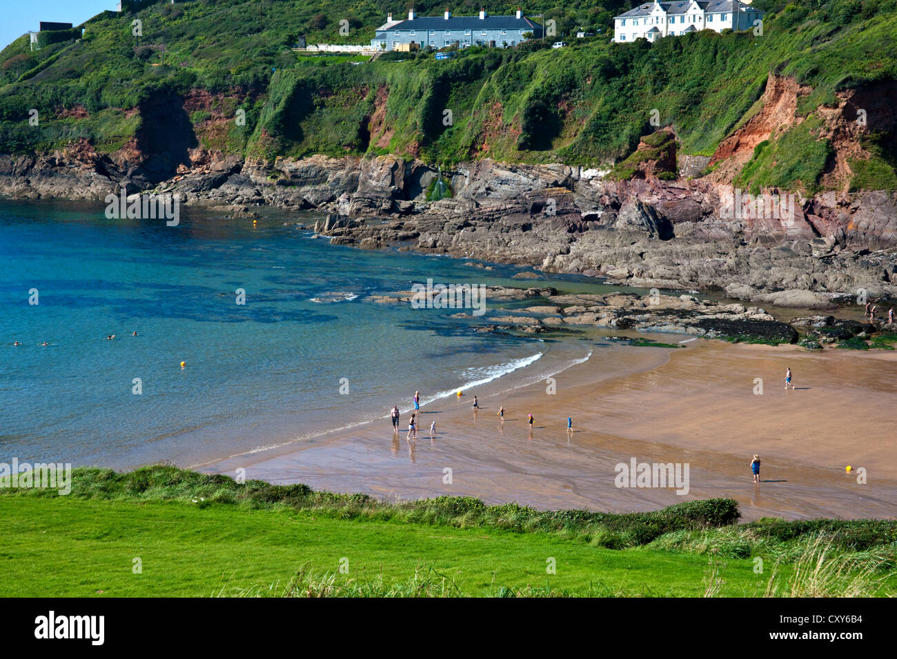 A sandy cove with surrounding cliffs and the sea rolling up the beach