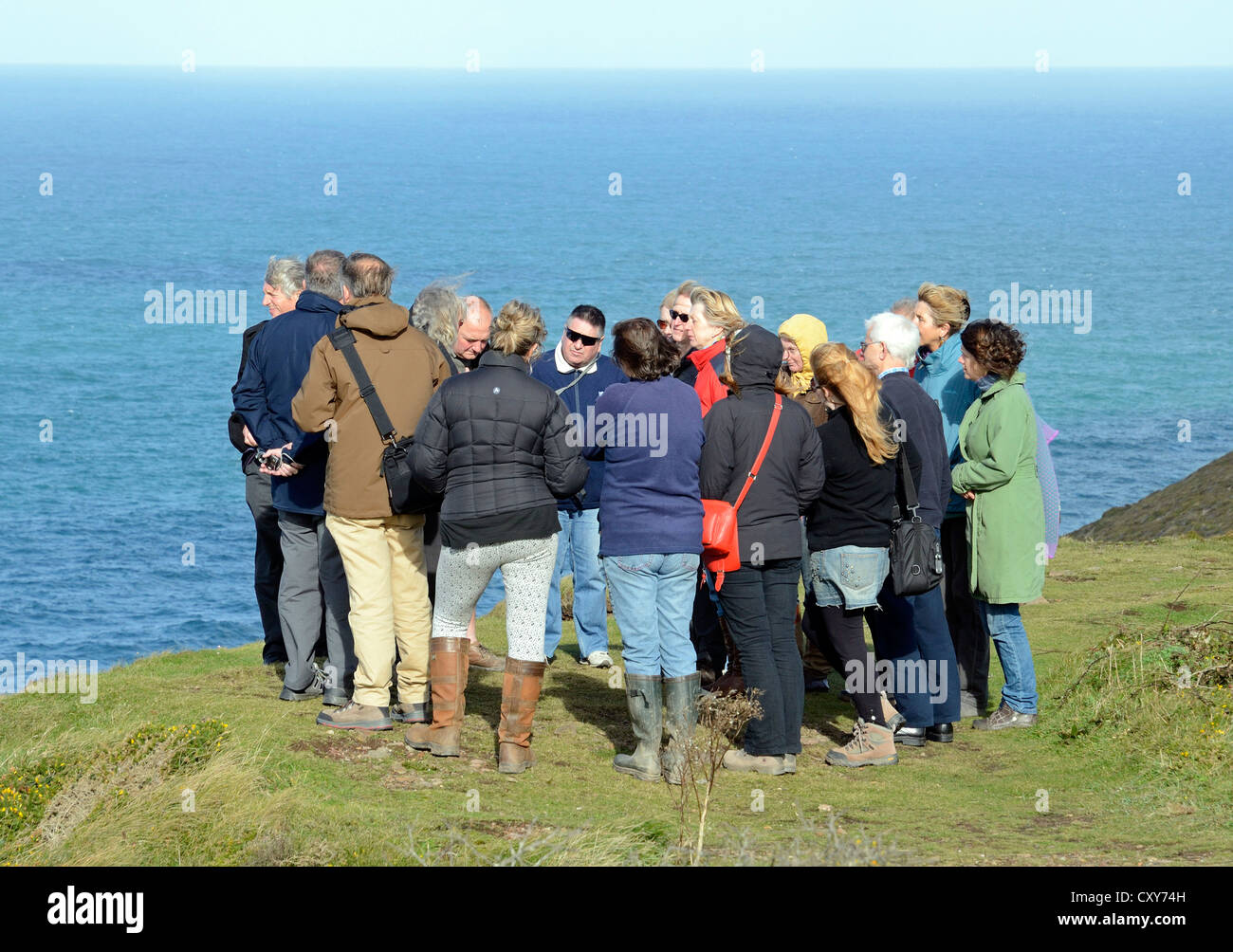 A group of tourists on the coastal cliffs of Cornwall, UK, during a guided tour of the counties tin mining area Stock Photo