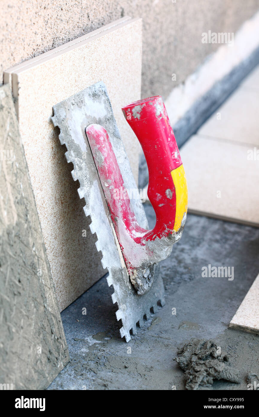mortar on wall construction notched trowel work tools Stock Photo