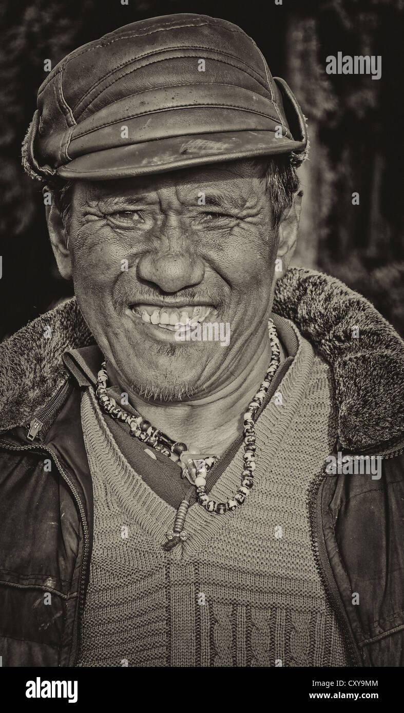 Old Nepali Buddhist Man, portrait, smiling, with cap, facing camera, copy space, outdoor, sunlight, Black and white Stock Photo