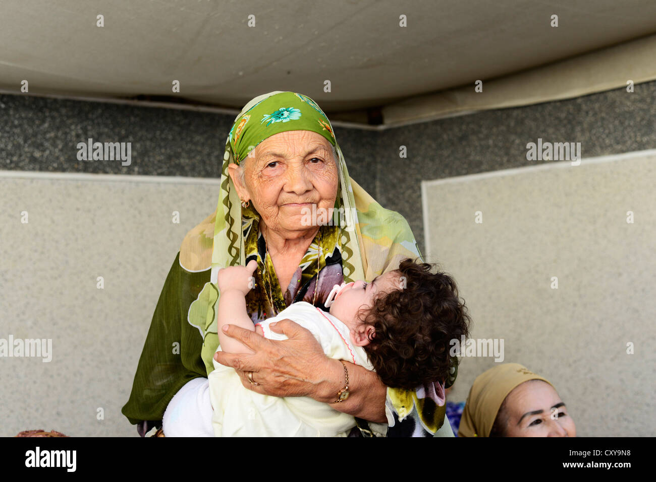 An old Tajik woman holding her grandchild. Stock Photo