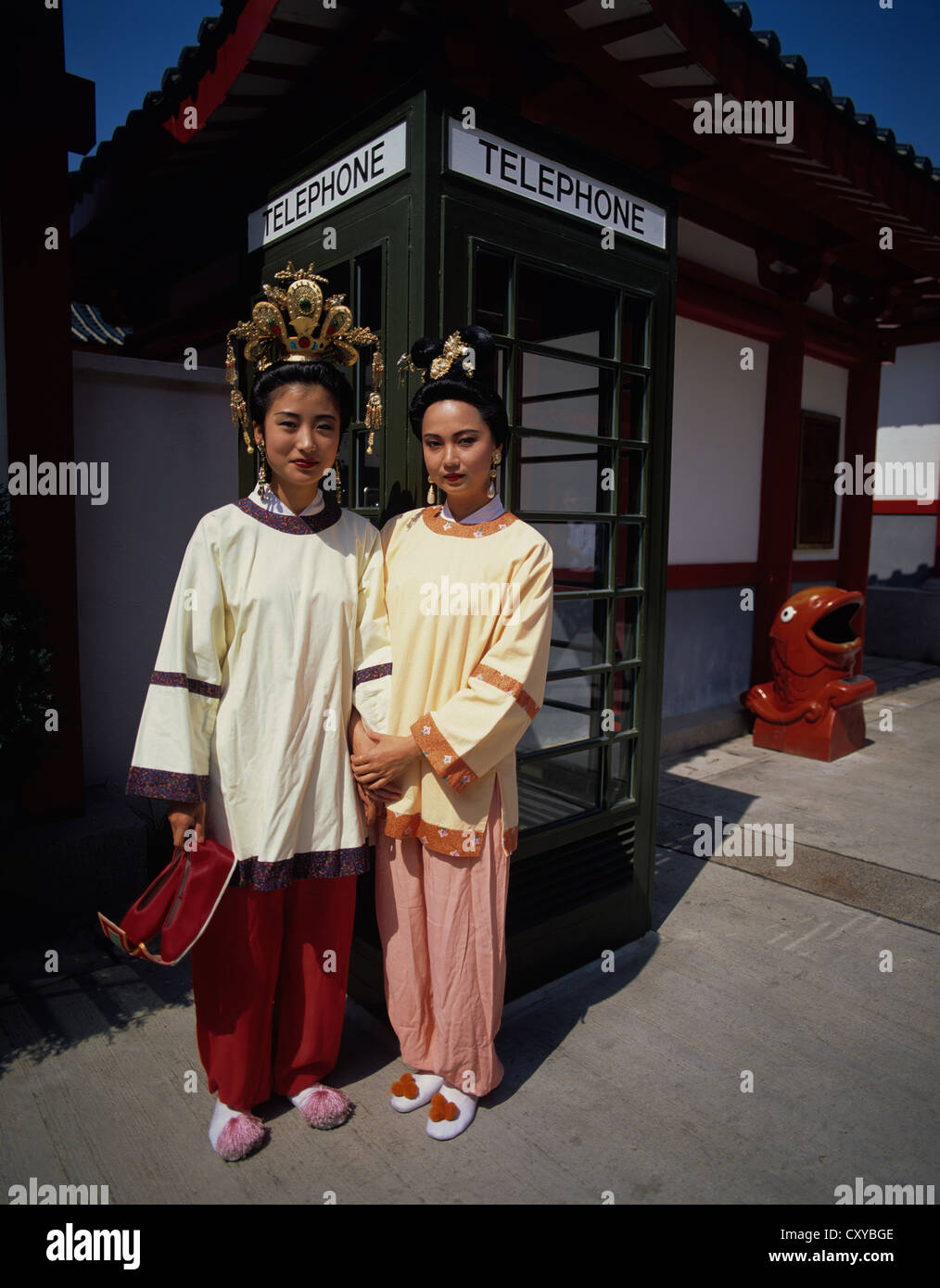 Hong Kong. Middle Kingdom. Two Chinese ladies in traditional Song Dynasty clothes. Posing by old English telephone booth in temp Stock Photo