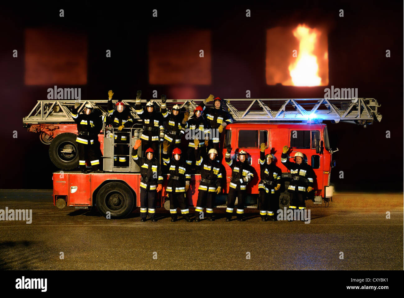 Firemen with a fire engine in front of a burning building Stock Photo -  Alamy