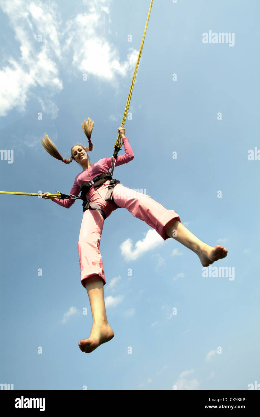 Young woman jumping with the ropes of a bungee trampoline Stock Photo