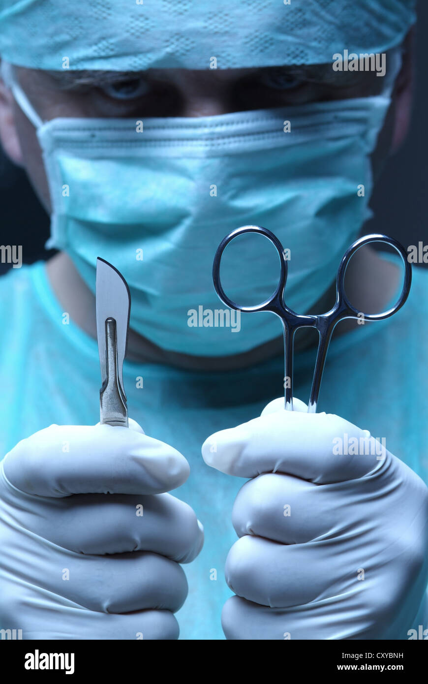 Surgeon wearing a face mask and holding a scalpel and a hemostatic