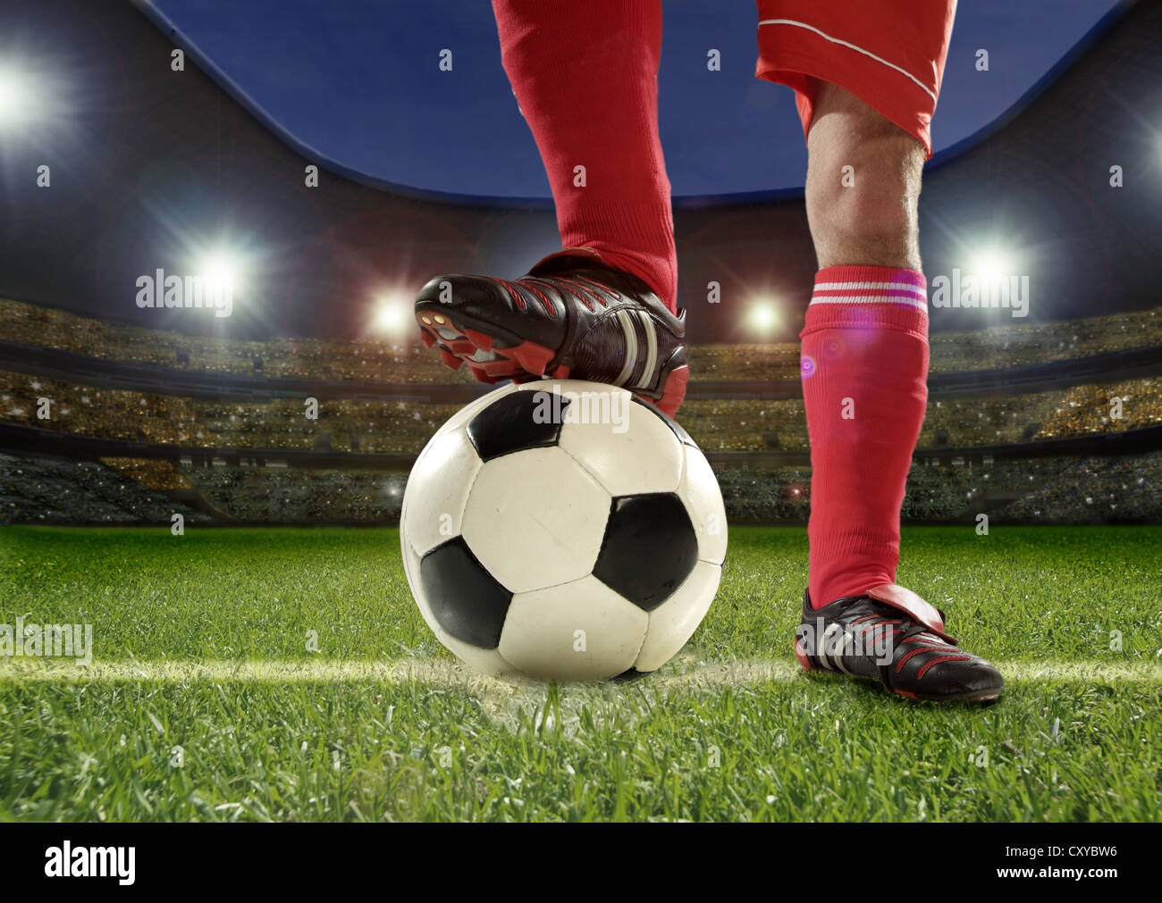 Football player, detail of legs, holding the ball with his foot in a football stadium Stock Photo