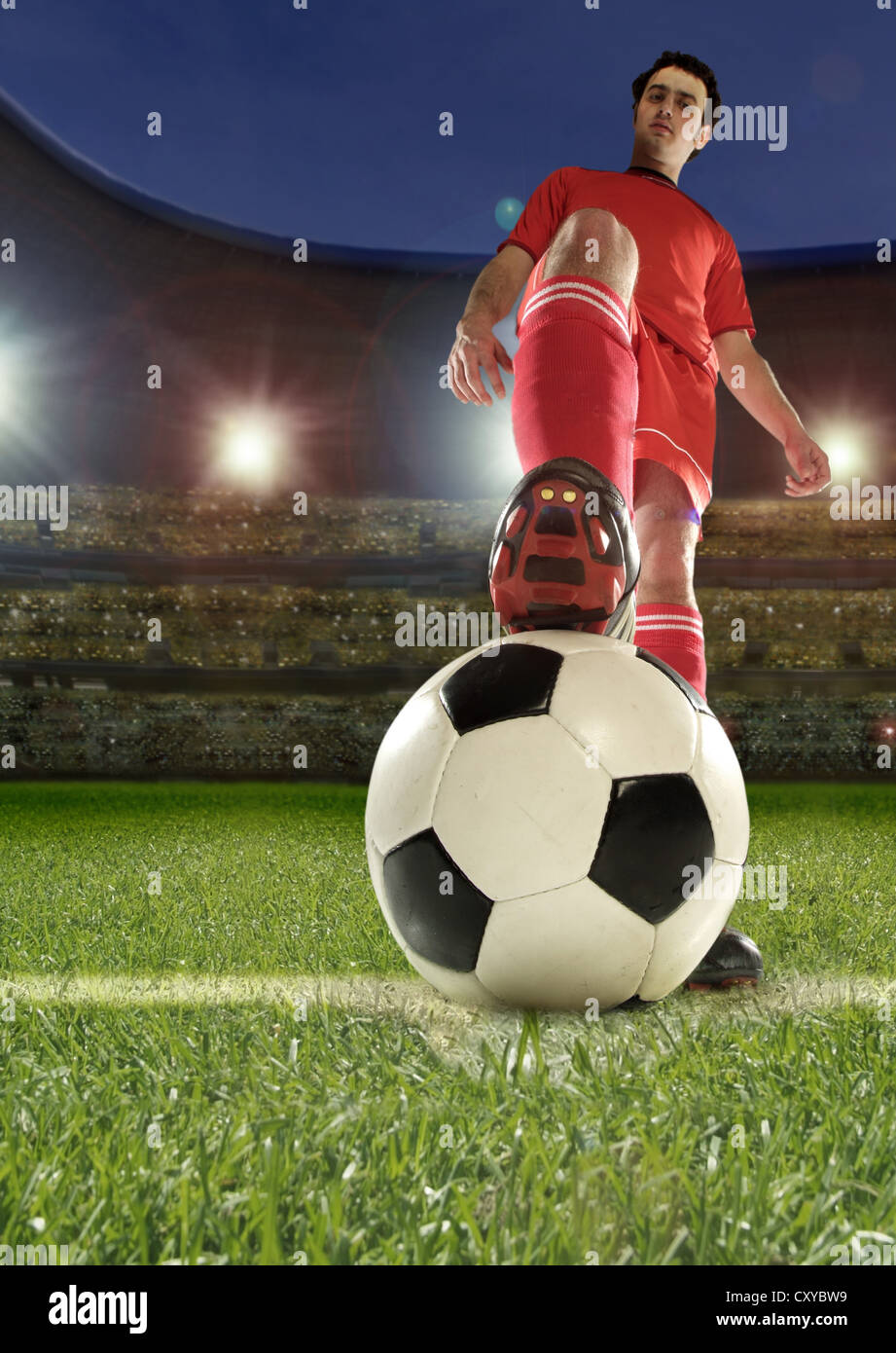 Football player holding the ball with his foot in a football stadium Stock Photo