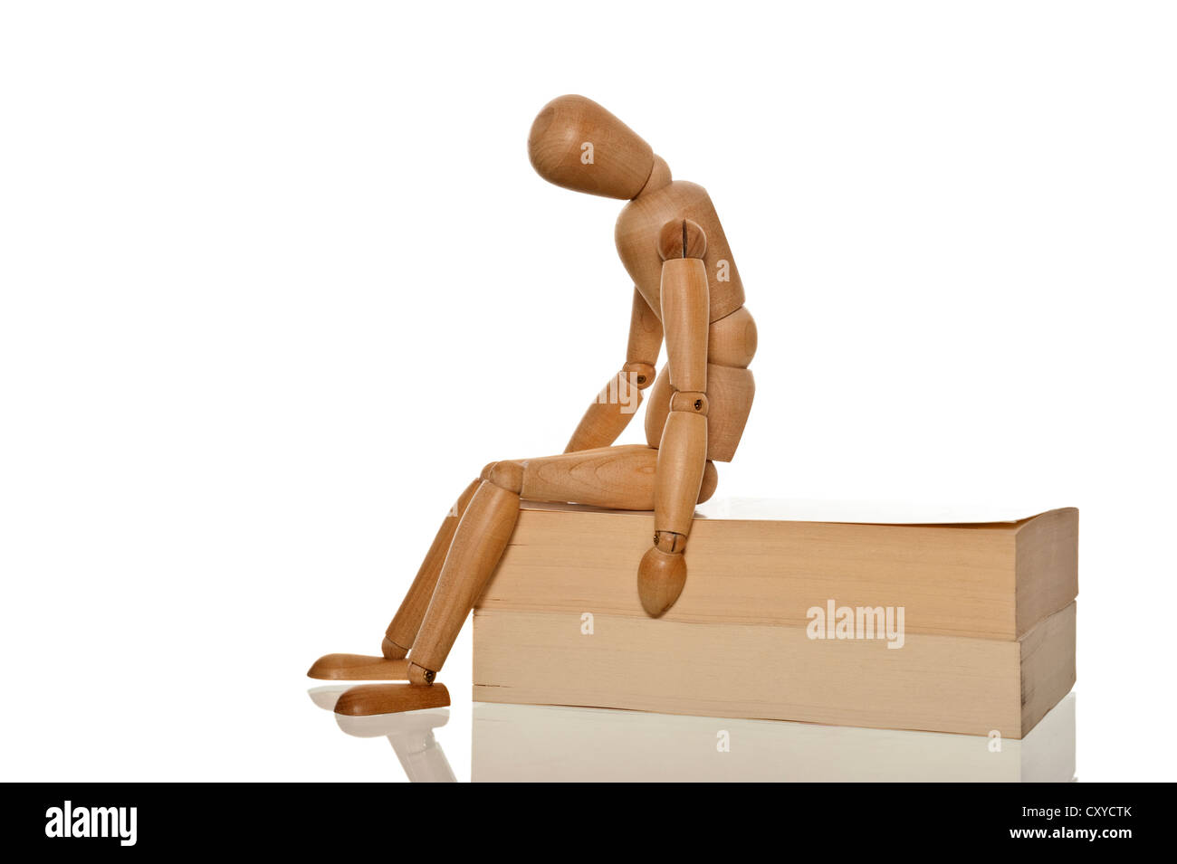 Mannequin looking desperate and exhausted while sitting on two books Stock Photo