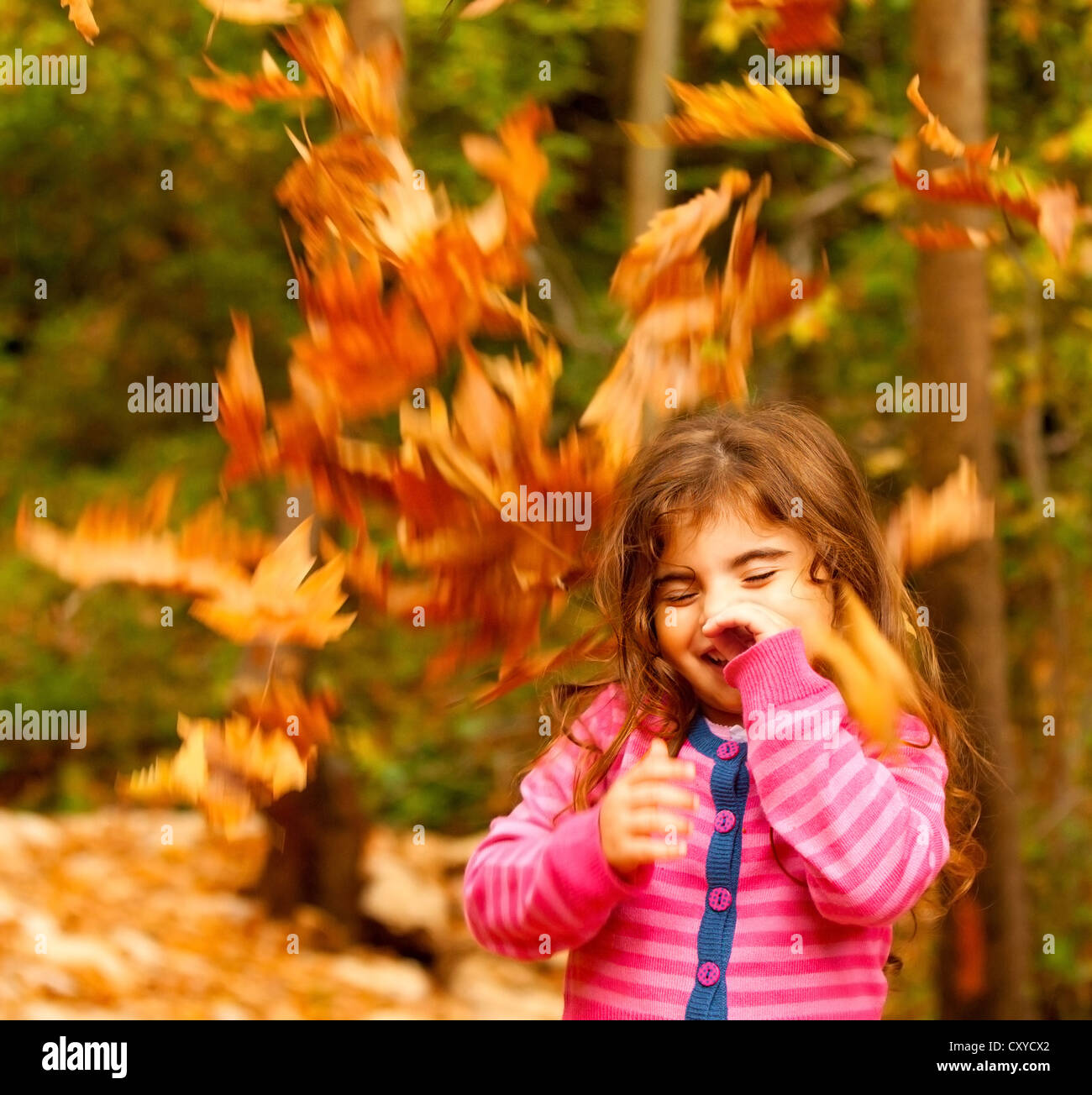 Image of small cute female child enjoying autumn nature, little pretty girl playing game in fall park, beautiful golden trees Stock Photo