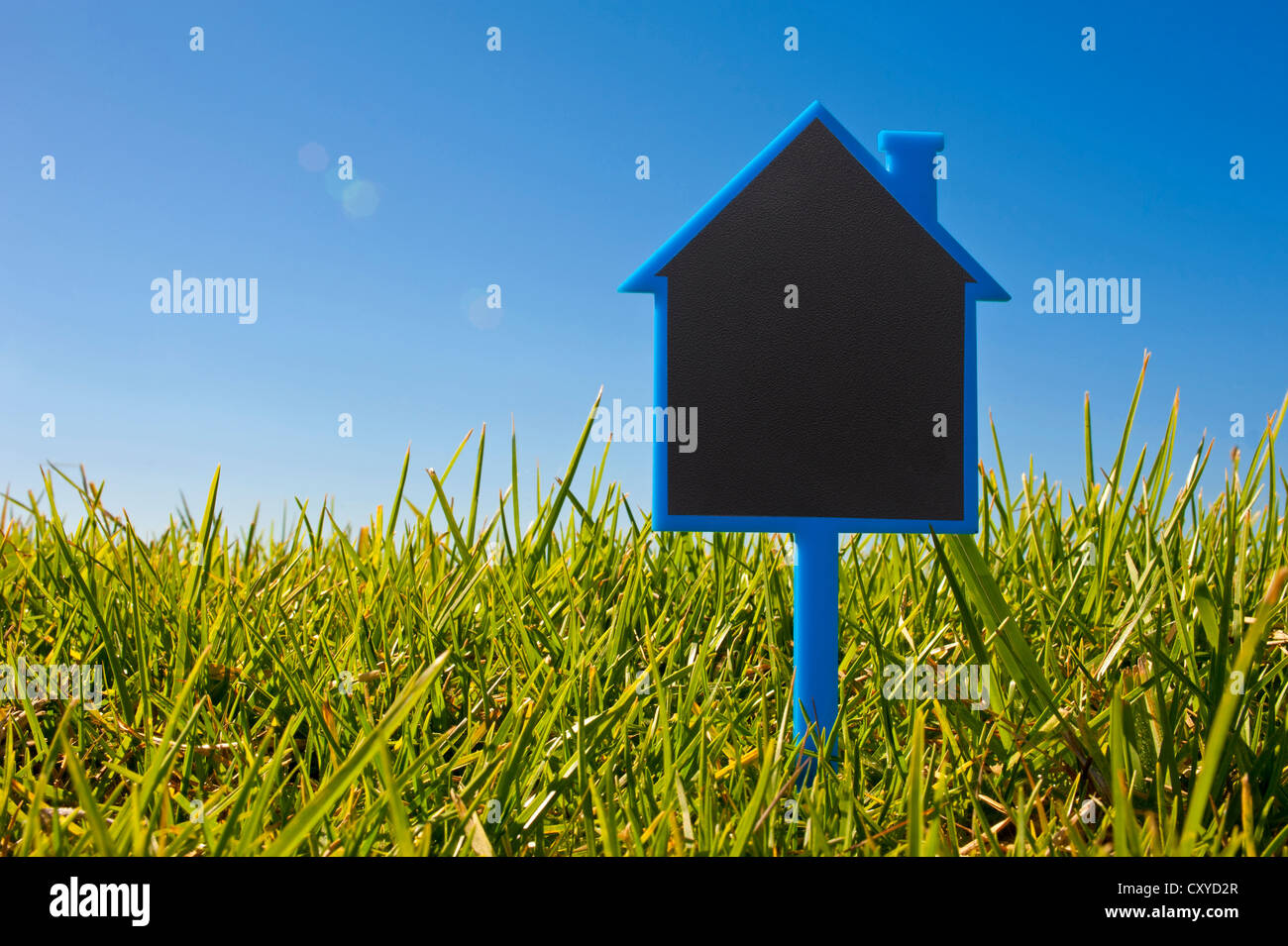 Blank sign shaped like a house in the grass, symbolic image for house