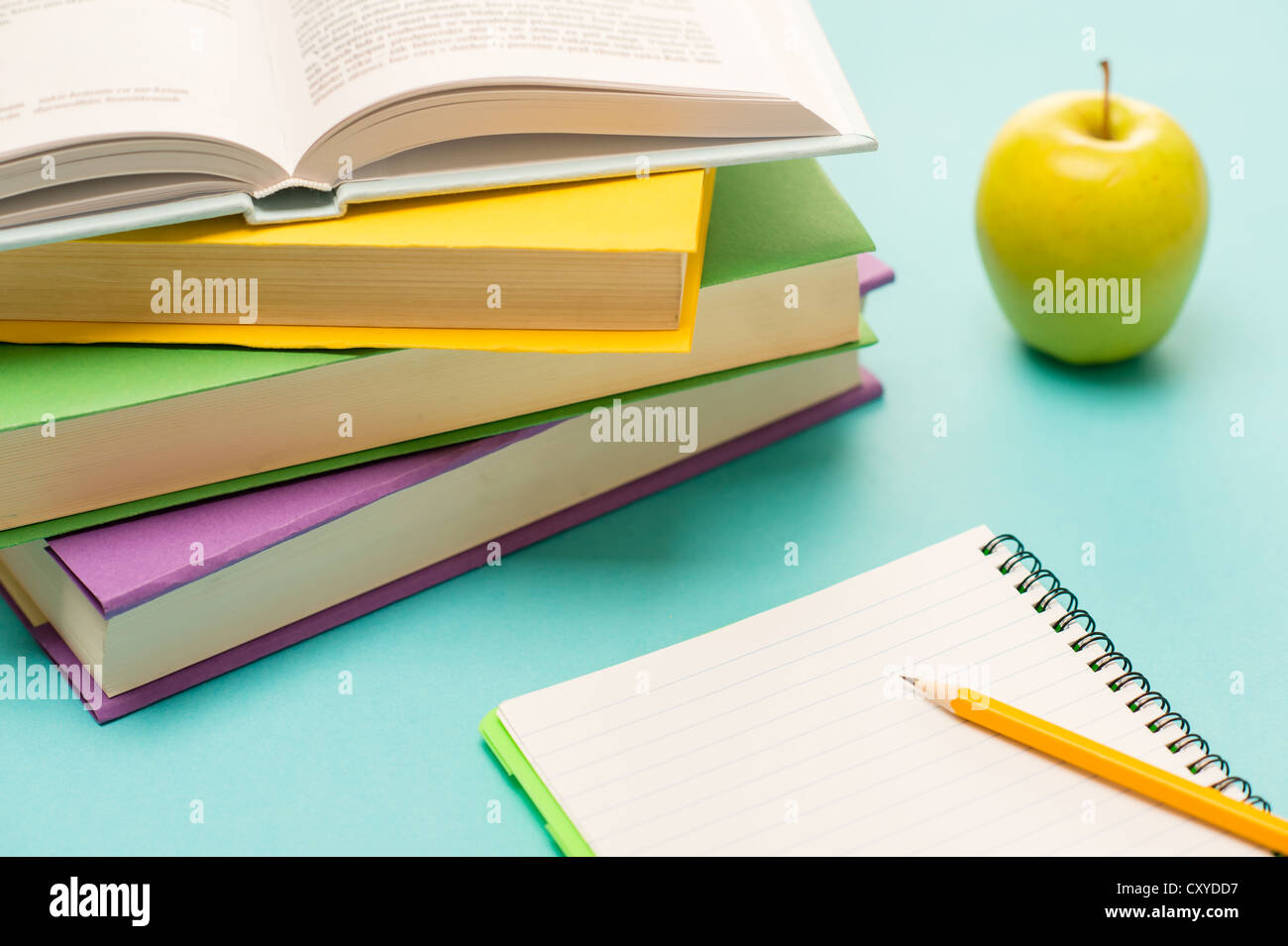 Pencil on notepad with school books and apple on student desk Stock Photo