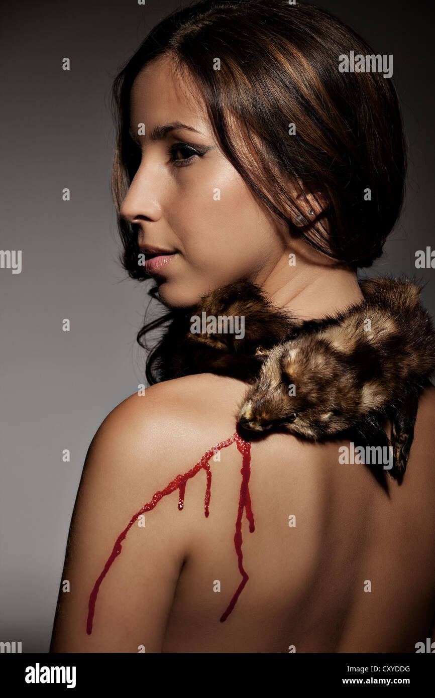Brown-haired woman with fur on her neck and blood on her body Stock Photo